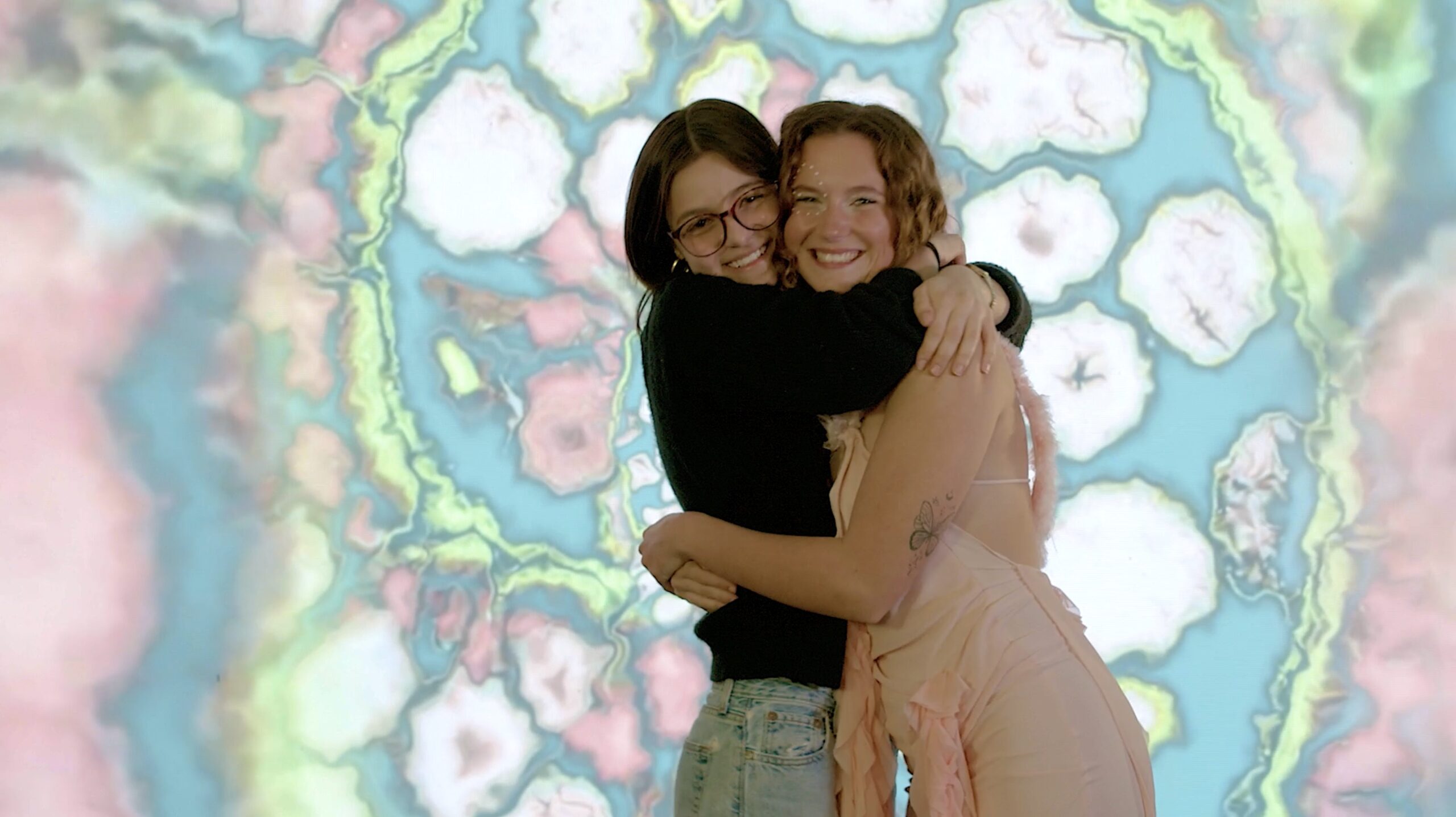 Melis and Model hugging in front of a spiraled background