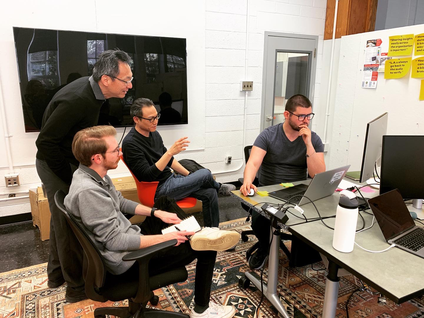 4 men sitting in a studio space discussing interactive work on a screen