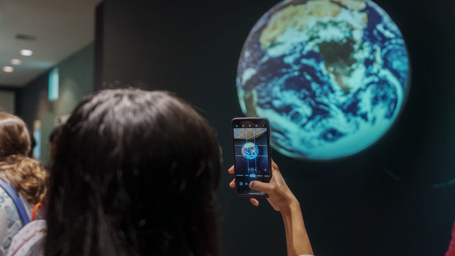 A student photographs the projection of the earth for use in their studio project.