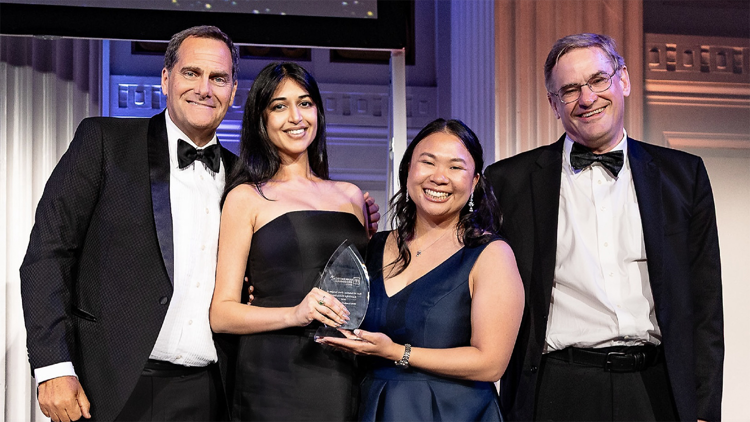 Four IBM team members hold an award in formal wear
