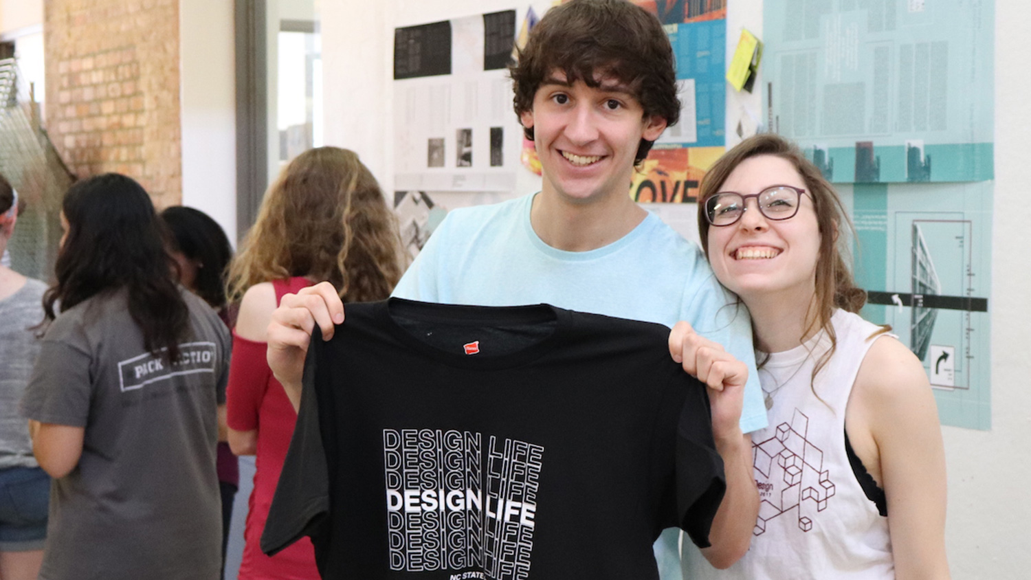 Students hold up DesignLife tshirt