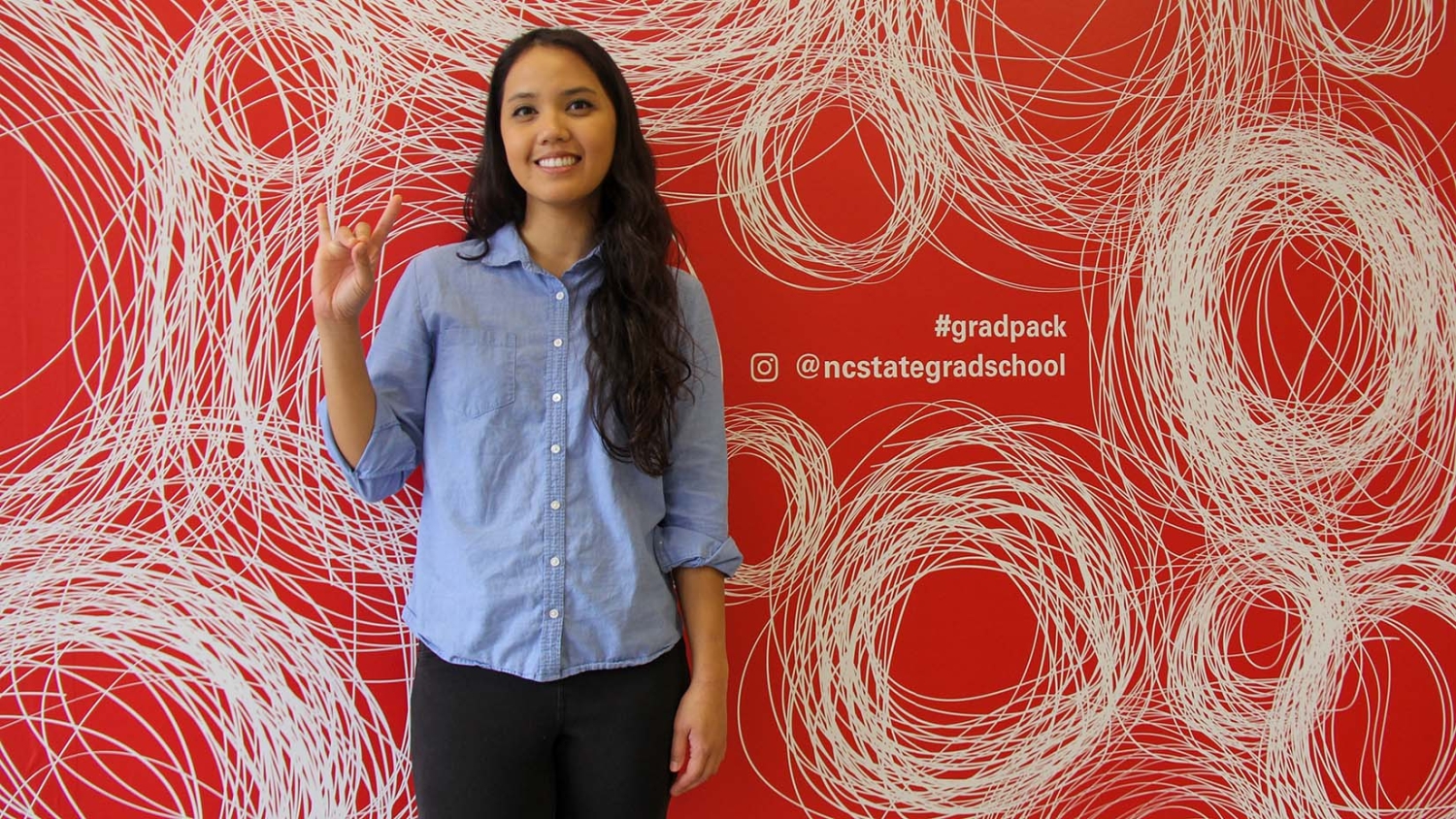 Carmina Ferreras standing in front of mural wall