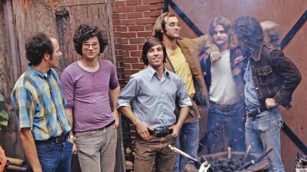 Mark Templeton (center) ’75 relaxes with friends while learning forging methods by the furnace.