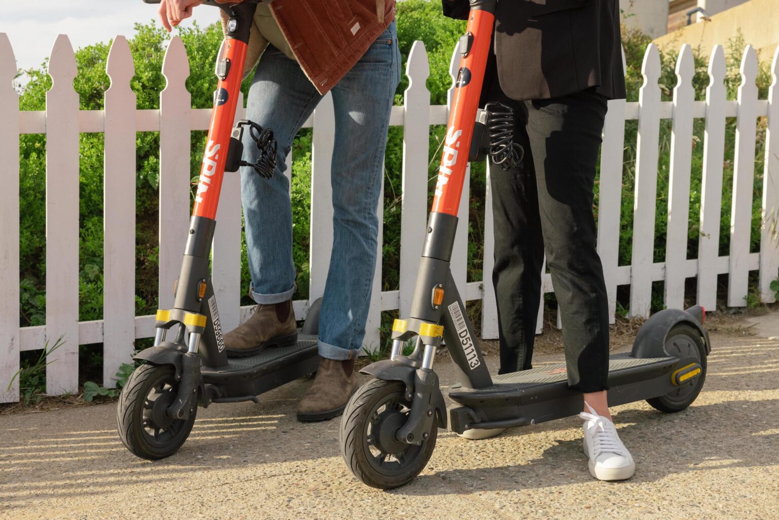 Two people using Spin e-scooters