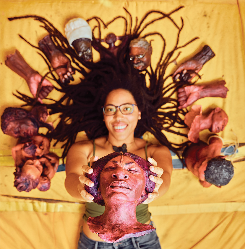 Dare Coulter ’15 with some of the head and hand sculptures she created to tell the story. Photograph by Joshua Steadman.
