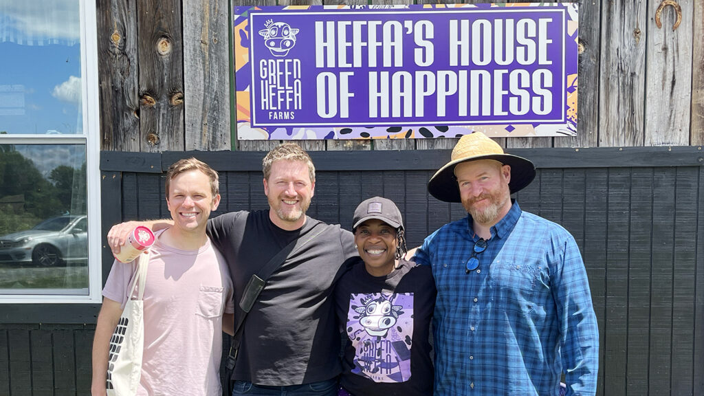 four people standing in front of a purple sign that reads "heffa's house of happiness"