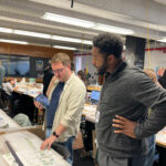 Andrew Holland looks over a student's work on the Paper Streets project.