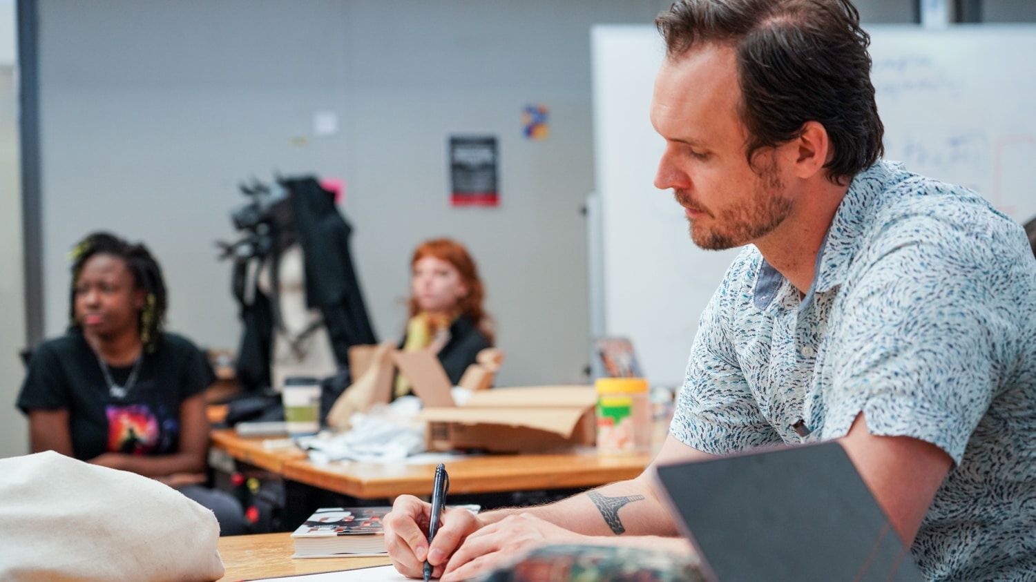 Justin Johnson takes notes as students present their work in a design class