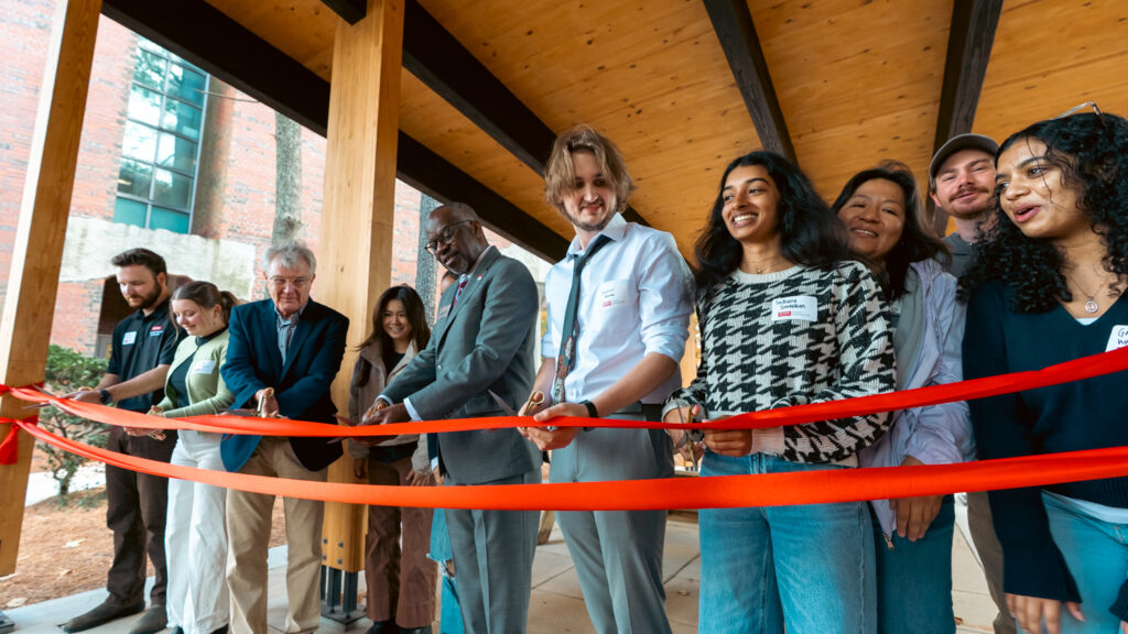 a group of students and instructors preparing to cut a red ribbon during a ceremony