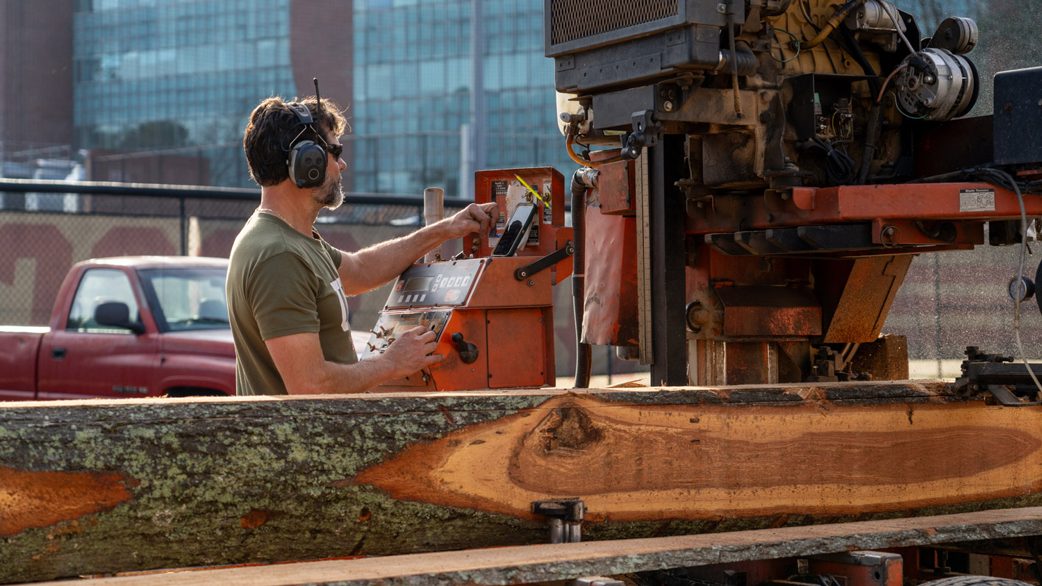 A machine operator manages cutting the wood into planks.